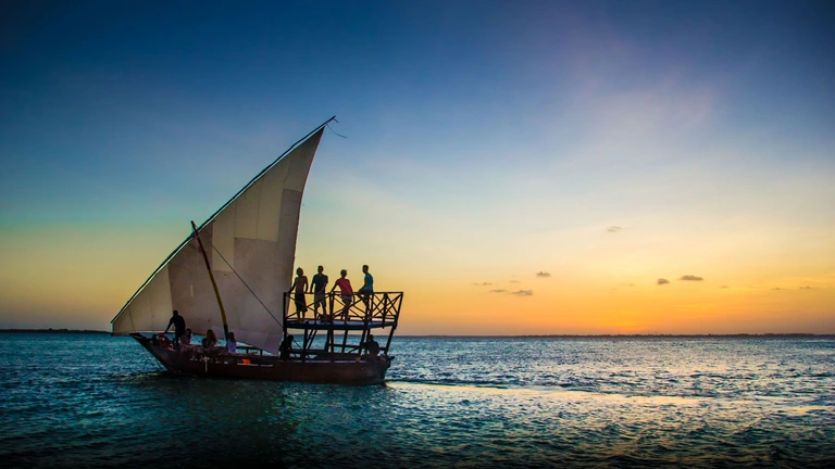 Traditional dhow sailing on Indian Ocean at sunrise off Zanzibar Tanzania